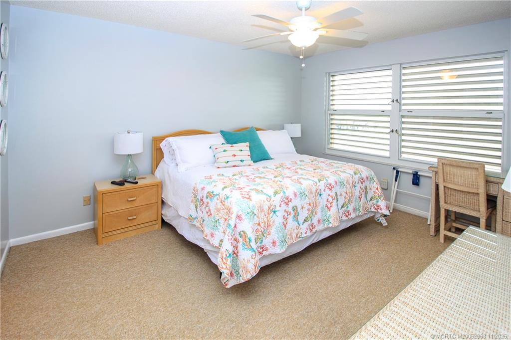 4540 Northeast Sandpebble Trace, Unit 203 Stuart, FL 34996 - Photo 11 of 30 a bedroom with a bed and a chandelier