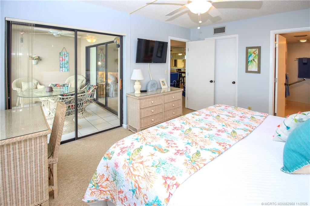 4540 Northeast Sandpebble Trace, Unit 203 Stuart, FL 34996 - Photo 12 of 30 a bedroom with a bed and glass door