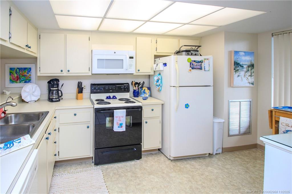 4540 Northeast Sandpebble Trace, Unit 203 Stuart, FL 34996 - Photo 15 of 30 a kitchen with stainless steel appliances a refrigerator sink and cabinets