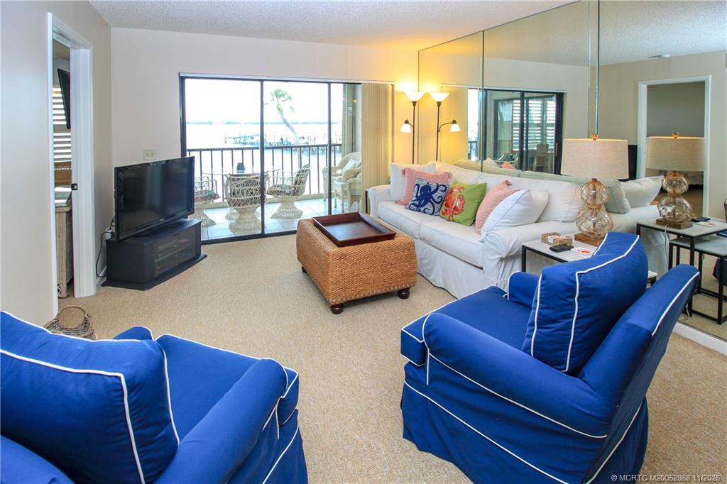4540 Northeast Sandpebble Trace, Unit 203 Stuart, FL 34996 - Photo 4 of 30 a living room with furniture a flat screen tv and a large window