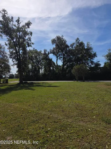 a white house with a small yard plants and large trees