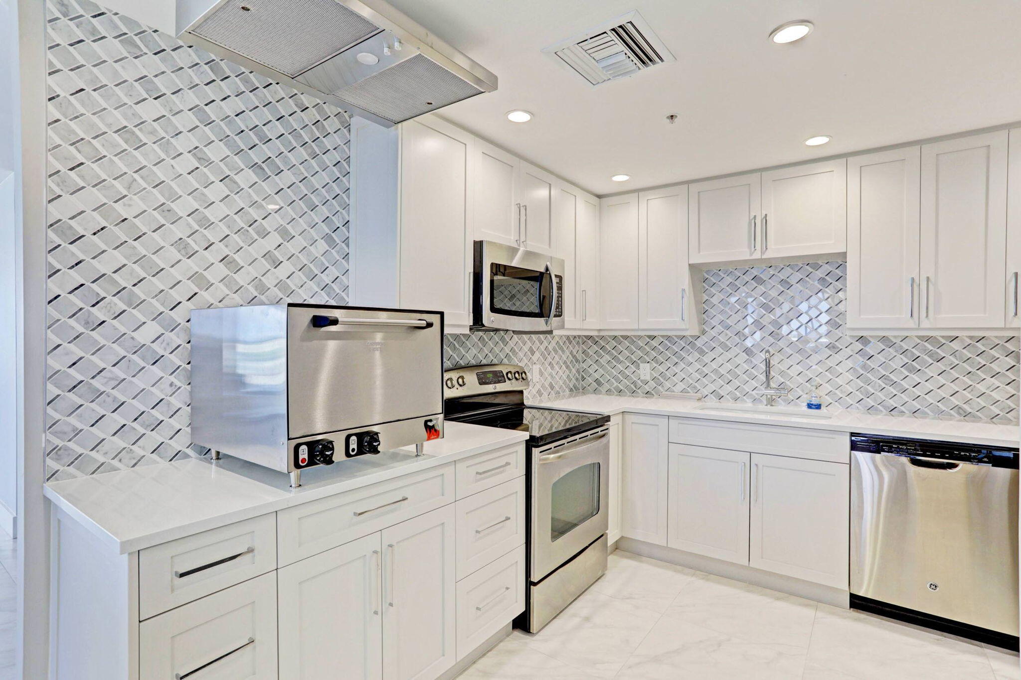5280 North Ocean Drive, Unit 14D Riviera Beach, FL 33404 - Photo 48 of 55 a kitchen with granite countertop white cabinets and white appliances