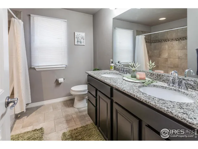 a bathroom with a granite countertop sink a toilet a mirror and shower