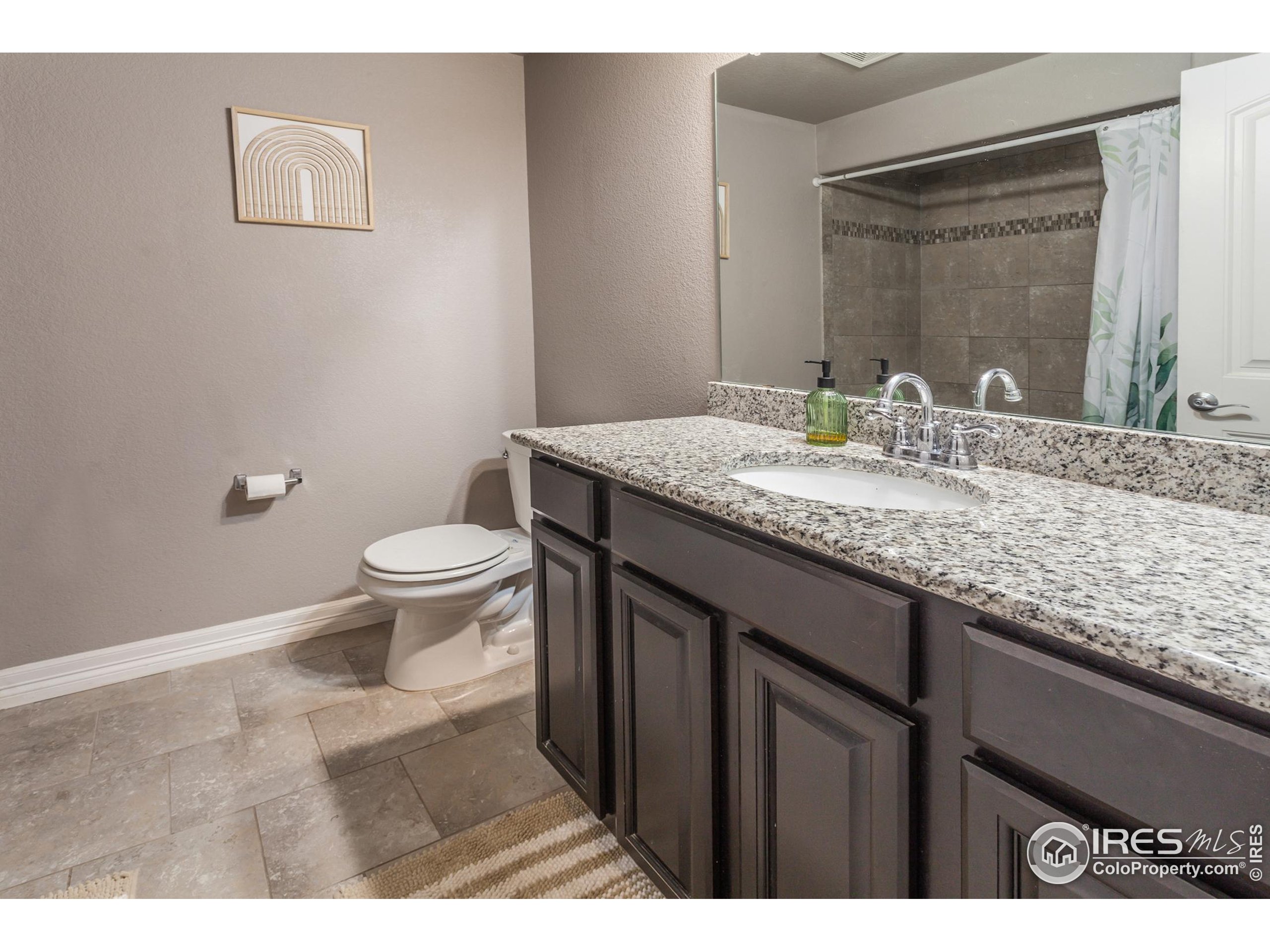 1297 Wild Basin Road Severance, CO 80550 - Photo 34 of 44 a bathroom with a granite countertop sink a toilet and a mirror