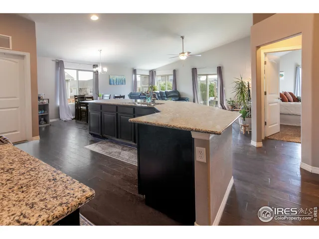 a open kitchen with stainless steel appliances granite countertop a stove a refrigerator a sink dishwasher and a dining table with wooden floor