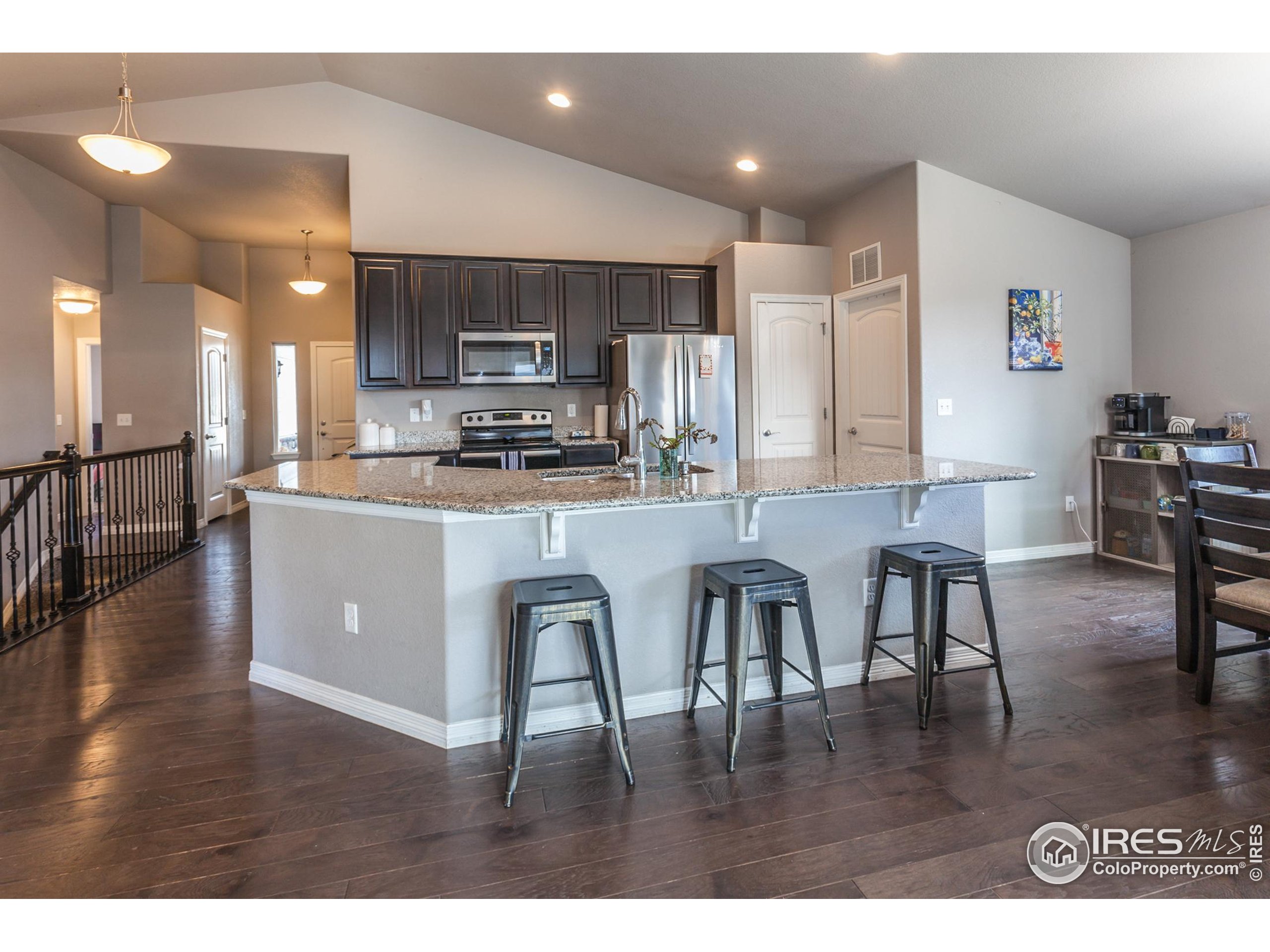 1297 Wild Basin Road Severance, CO 80550 - Photo 5 of 44 a kitchen with stainless steel appliances granite countertop a refrigerator a stove a sink a dining table and chairs with wooden floor