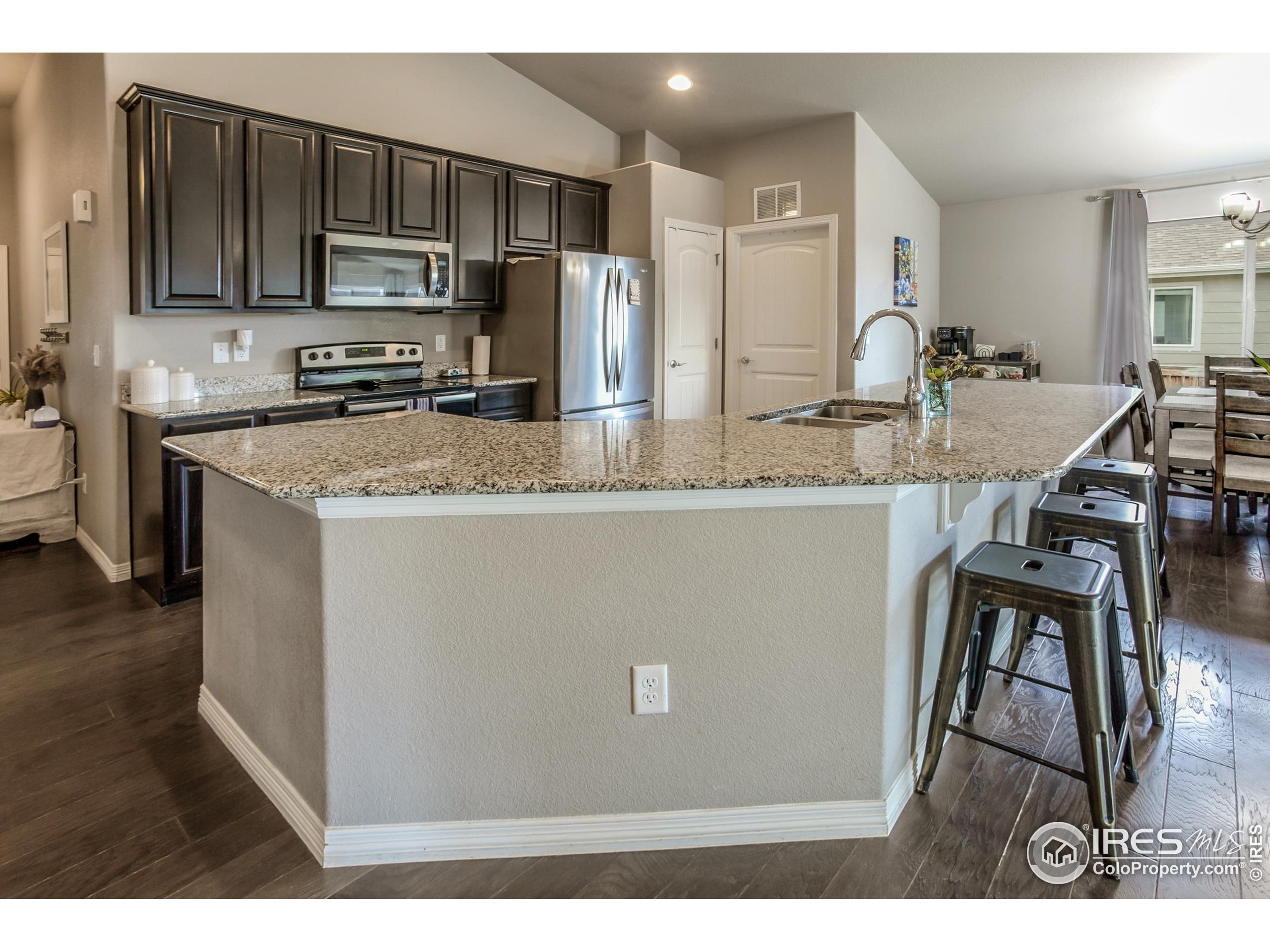 1297 Wild Basin Road Severance, CO 80550 - Photo 9 of 44 a kitchen with stainless steel appliances granite countertop a refrigerator a stove a sink a dining table and chairs