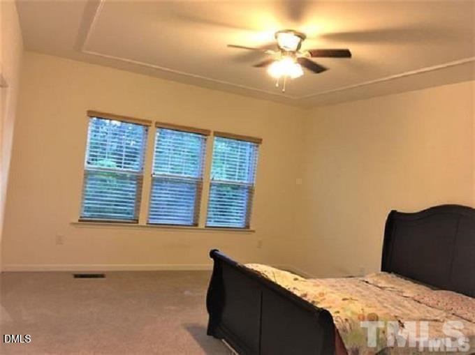 725 Edgewater Ridge Court Apex, NC 27523 - Photo 9 of 22 a bedroom with a bed and a chandelier