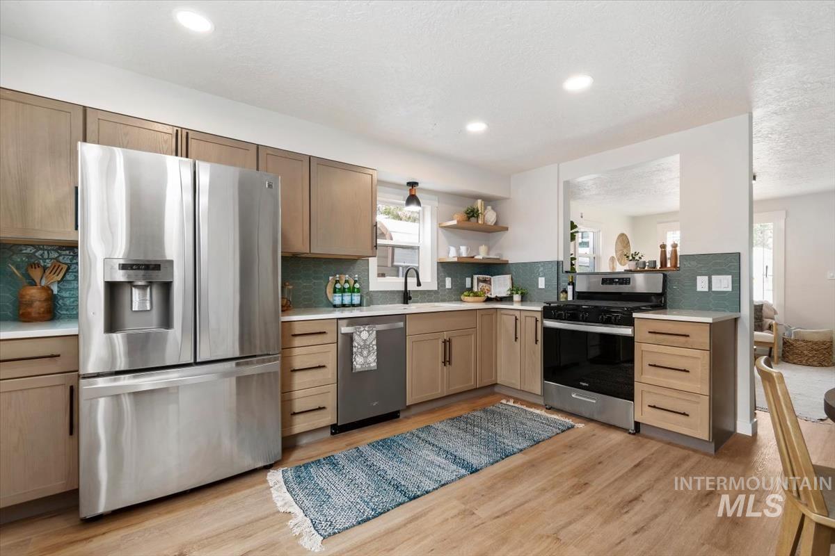 3005 West Hester Street Boise, ID 83702 - Photo 12 of 32 Kitchen featuring stainless steel appliances, light wood-finish cabinetry, white countertops, and a teal tile backsplash