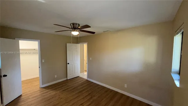 an empty room with wooden floor and windows with curtains