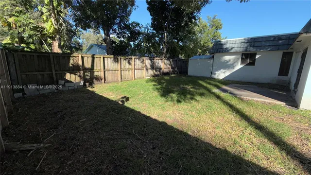 a view of backyard with green space and wooden fence