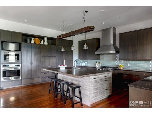 a kitchen with stainless steel appliances granite countertop a sink a stove and a wooden floors