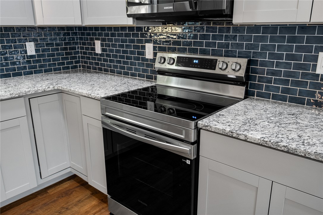 1215 East Whitner Street Anderson, SC 29624 - Photo 14 of 30 This kitchen boasts beautiful granite countertops and a sleek electric range, perfect for any culinary enthusiast.