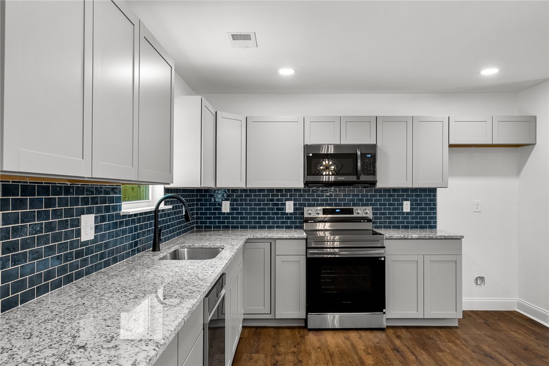 1215 East Whitner Street Anderson, SC 29624 - Photo 16 of 30 This modern kitchen features sleek countertops, stylish cabinetry, and essential appliances for comfortable living.
