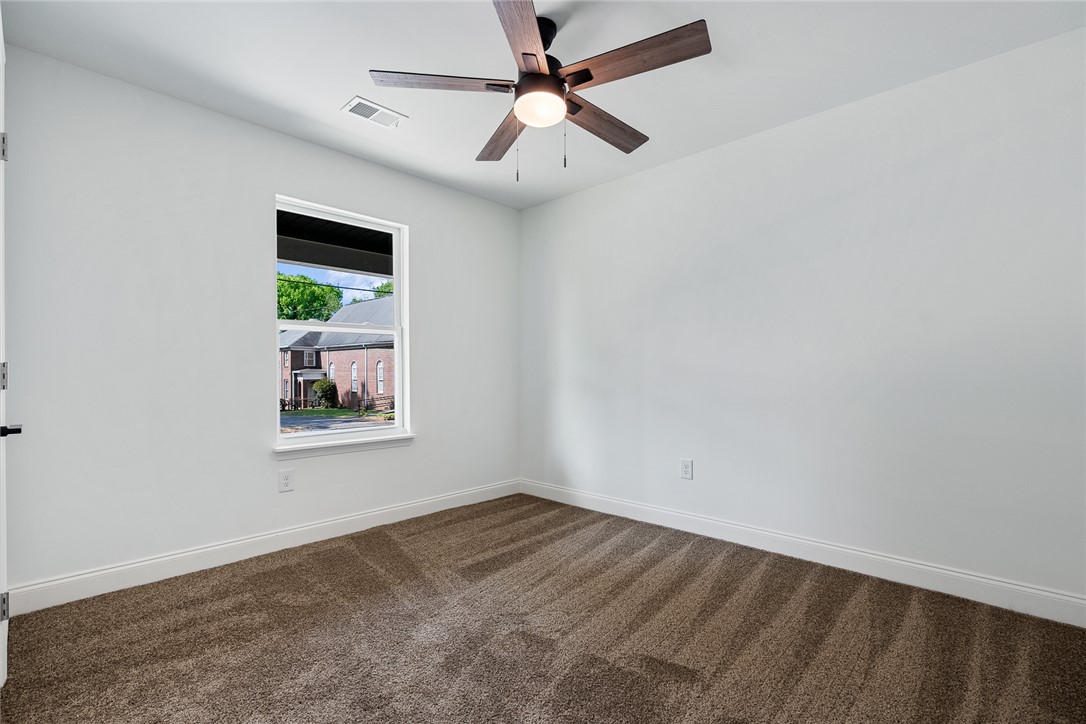 1215 East Whitner Street Anderson, SC 29624 - Photo 23 of 30 This airy bedroom offers a tranquil retreat, featuring plush carpeting and a bright window.