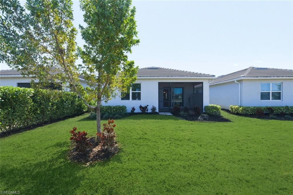 28310 Captiva Shell Loop Bonita Springs, FL 34135 - Photo 28 of 44 Rear view of property featuring stucco siding, a lawn, a sunroom, and a tile roof