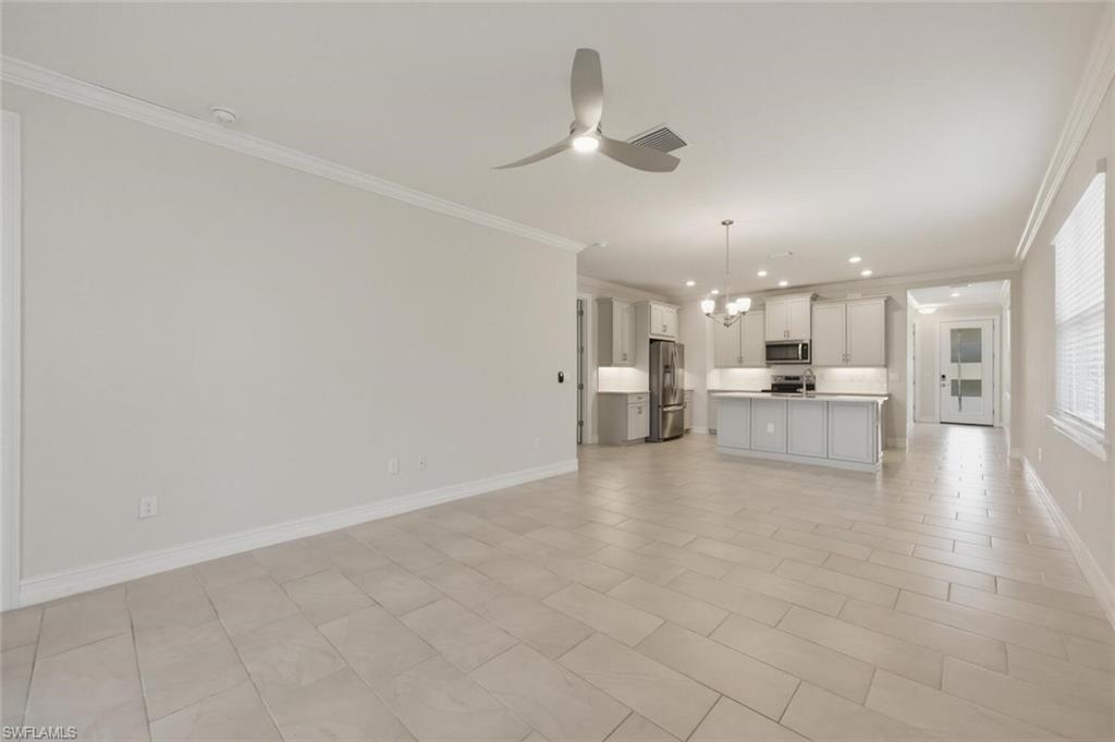 28310 Captiva Shell Loop Bonita Springs, FL 34135 - Photo 7 of 44 Unfurnished living room featuring suspended lighting, crown molding, and a ceiling fan