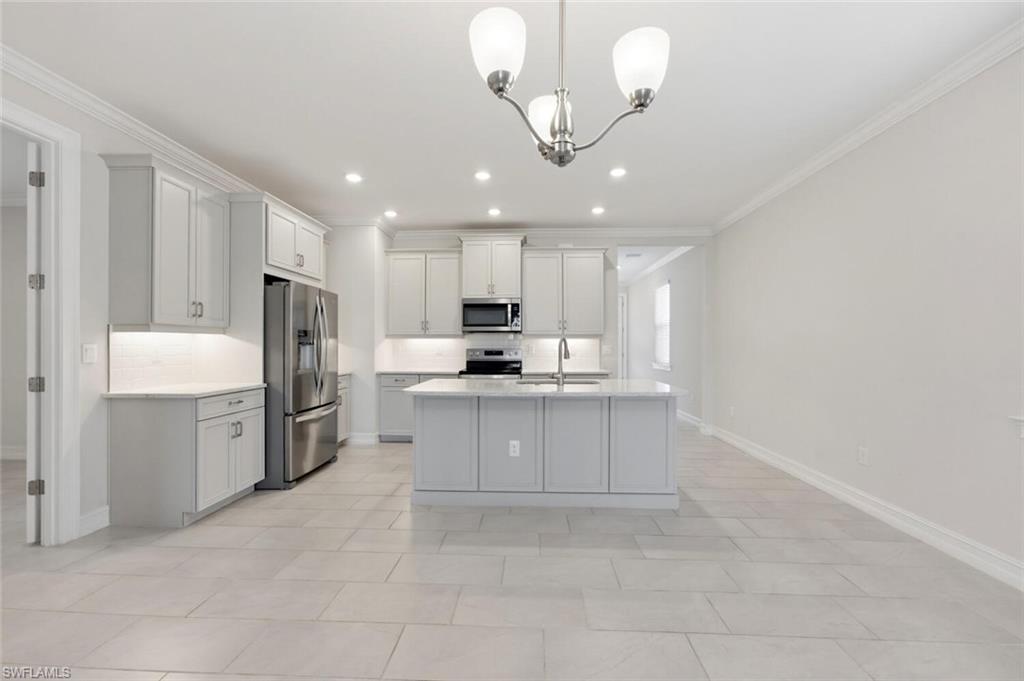 28310 Captiva Shell Loop Bonita Springs, FL 34135 - Photo 8 of 44 Kitchen with stainless steel appliances, ornamental molding, hanging lights, an island with sink, and decorative backsplash