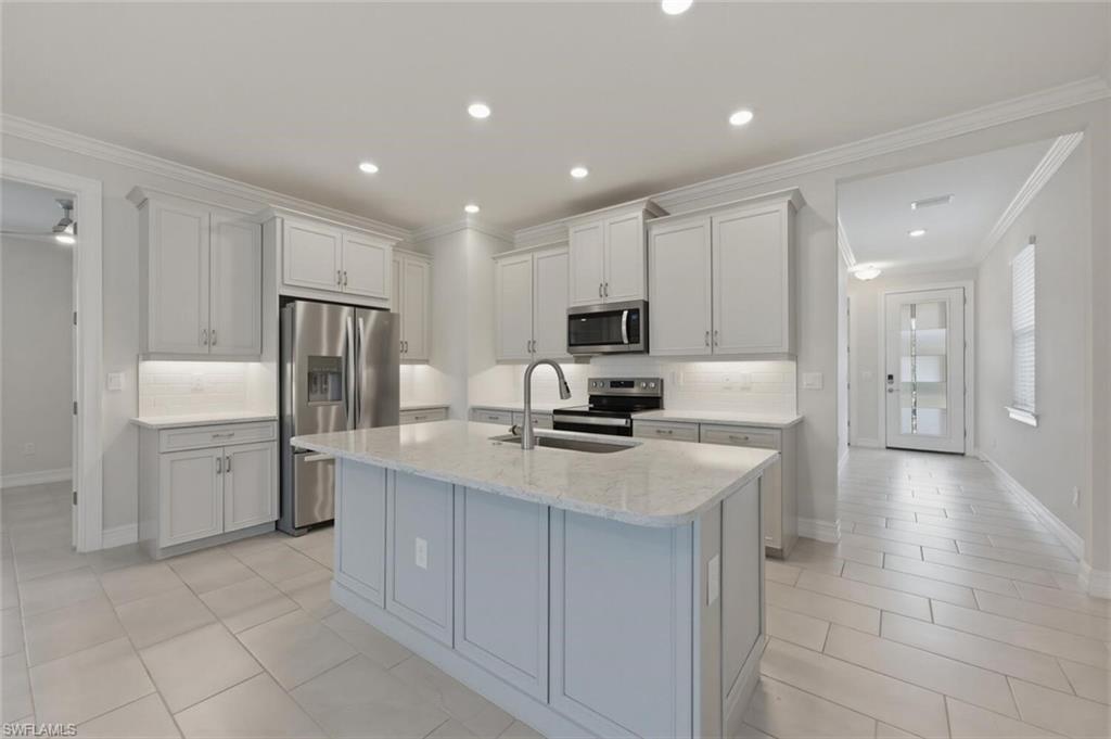 28310 Captiva Shell Loop Bonita Springs, FL 34135 - Photo 9 of 44 Kitchen with backsplash, ornamental molding, stainless steel appliances, light stone countertops, and recessed lighting