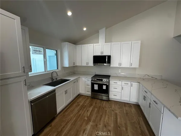 a large kitchen with kitchen island a sink stainless steel appliances and white cabinets