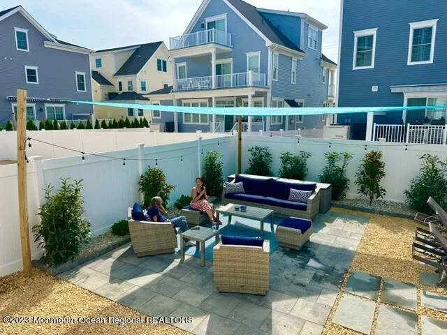 a front view of house with yard outdoor seating and covered with trees in the background