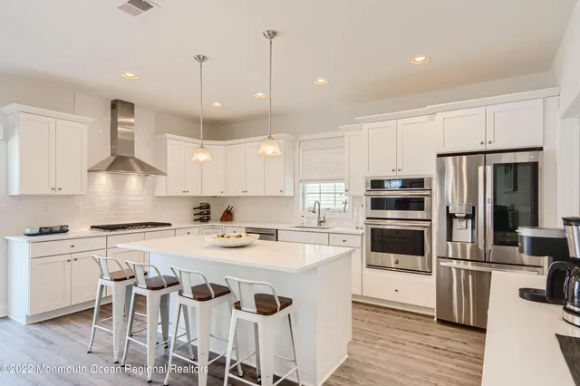 a kitchen with a center island appliances wooden floor and a counter top space
