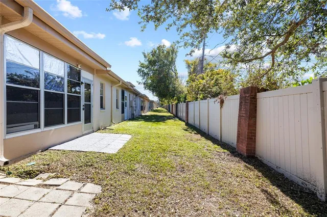 a view of a backyard with large trees and wooden fence
