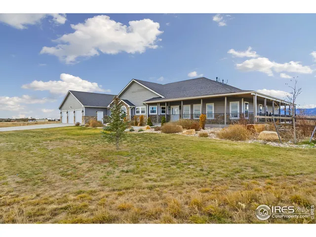 a view of a large pool with lawn chairs under an umbrella
