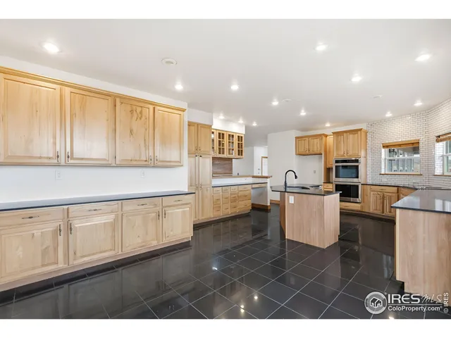 a open kitchen with white cabinets a sink dishwasher a dining table and chairs with wooden floor