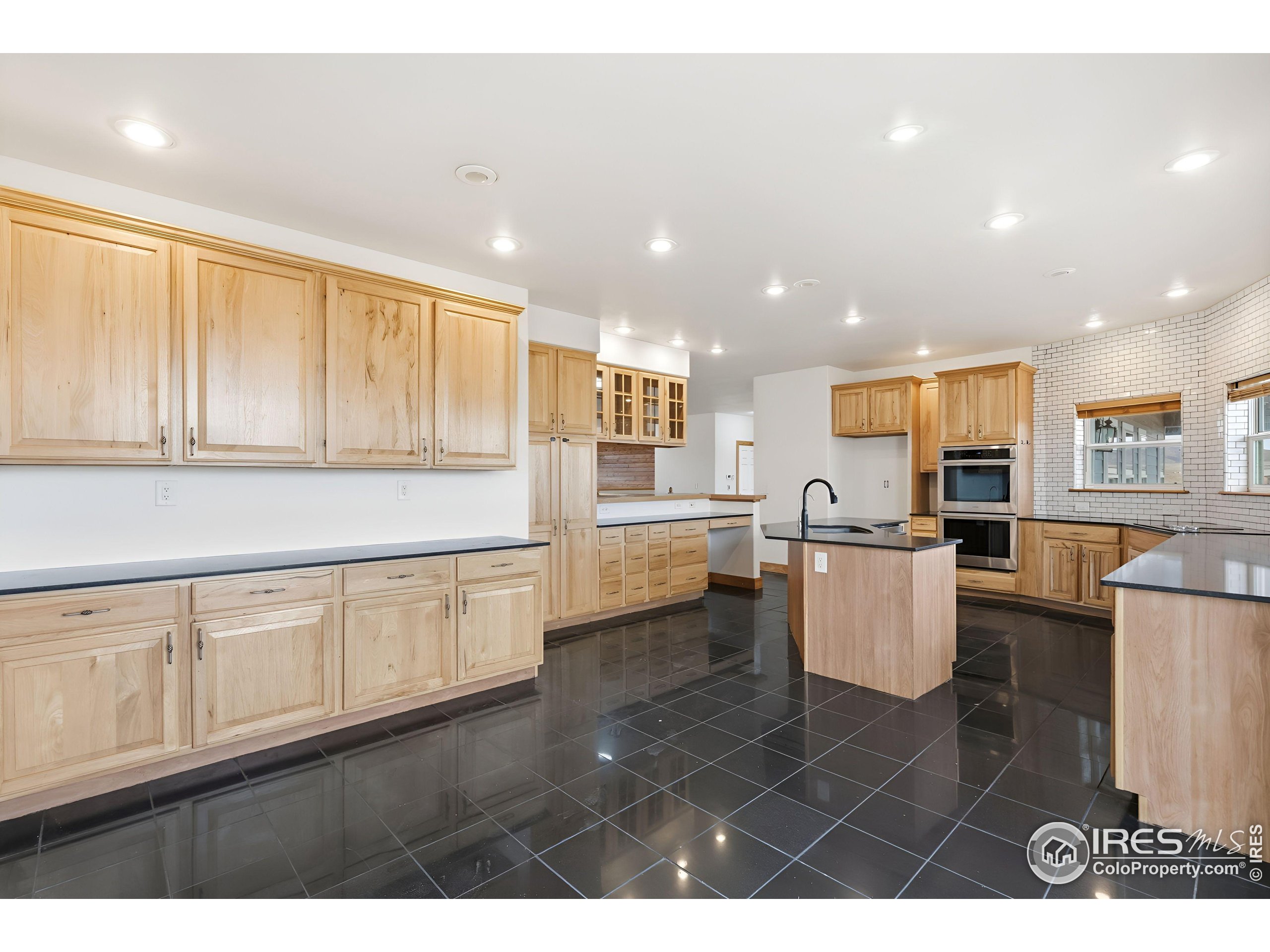 7321 Gilmore Avenue Fort Collins, CO 80524 - Photo 12 of 37 a open kitchen with white cabinets a sink dishwasher a dining table and chairs with wooden floor