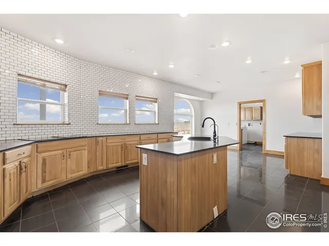 a kitchen with granite countertop a stove a sink a refrigerator and white cabinets with wooden floor