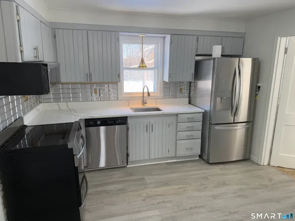 a kitchen with stainless steel appliances granite countertop a refrigerator a stove a sink and a microwave