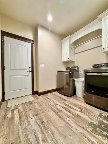 2101 Goose Ranch Road Vernal, UT 84078 - Photo 48 of 72 Laundry area featuring wood-finish flooring, white paneled door with dark trim, and built-in white cabinetry