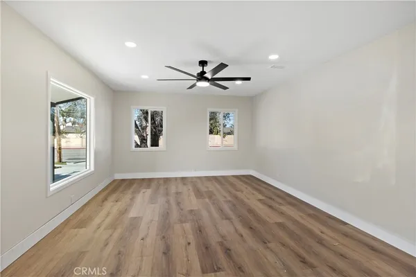 an empty room with wooden floor and windows