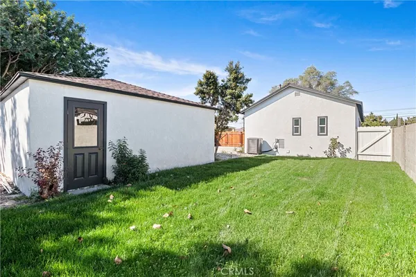 a view of a white house with a big yard plants and large trees