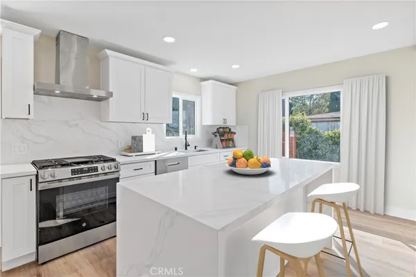 a kitchen with stainless steel appliances a stove a table and chairs