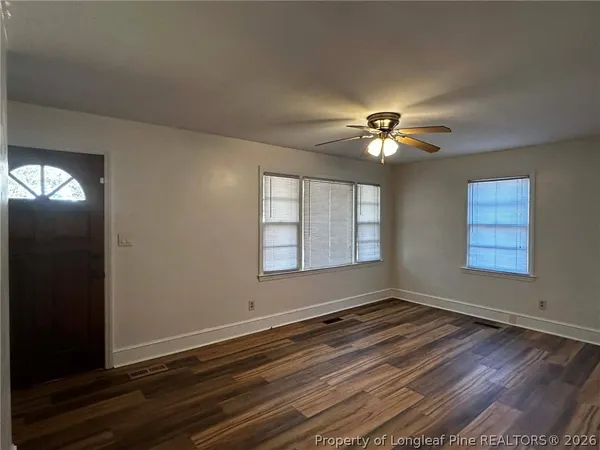 an empty room with wooden floor and windows