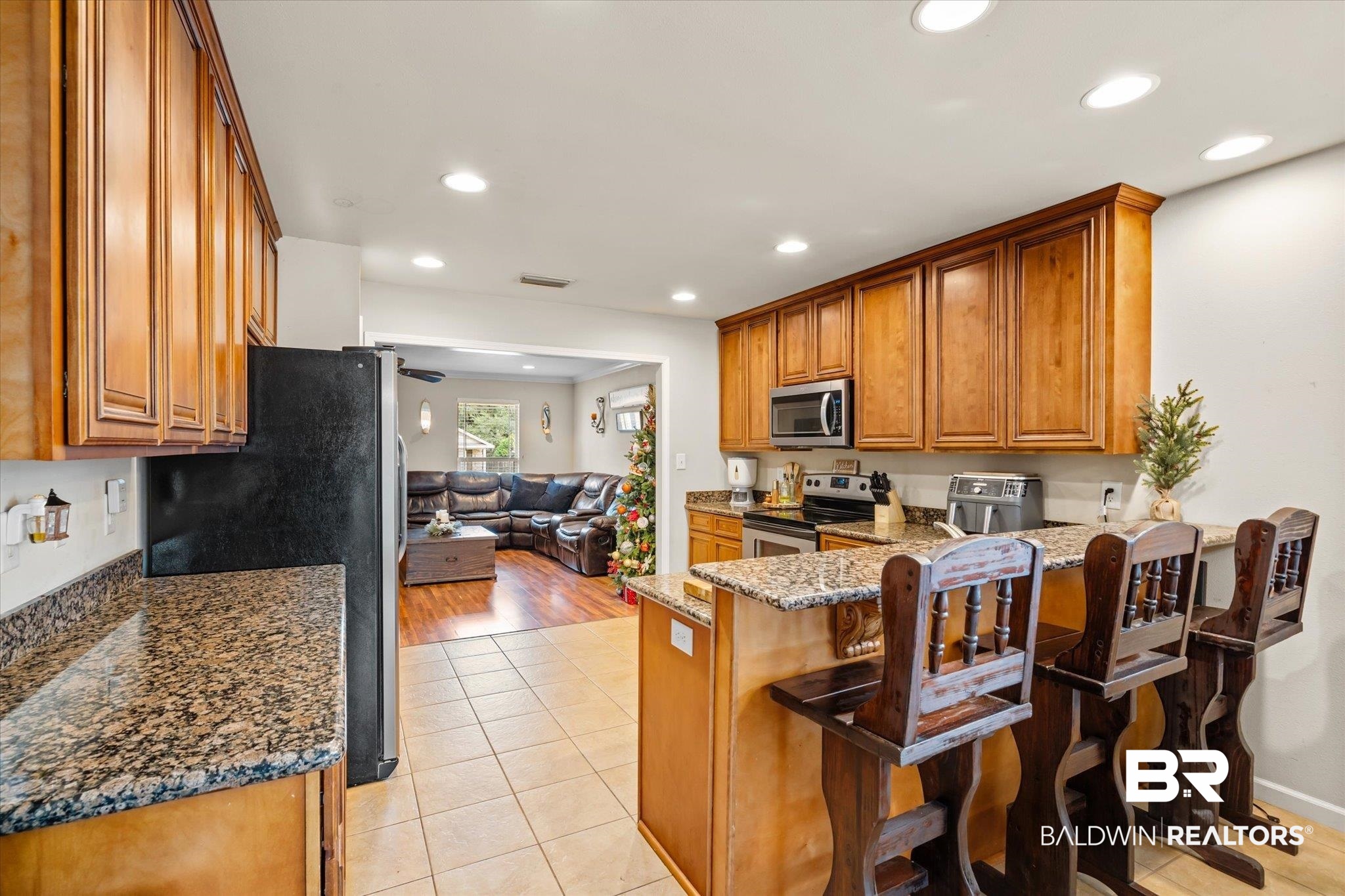 2855 Rebecca Drive West Mobile, AL 36618 - Photo 6 of 22 Kitchen with light hardwood / wood-style flooring, kitchen peninsula, dark stone counters, a kitchen bar, and appliances with stainless steel finishes