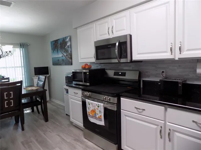 a kitchen with stainless steel appliances granite countertop a stove a sink and a microwave
