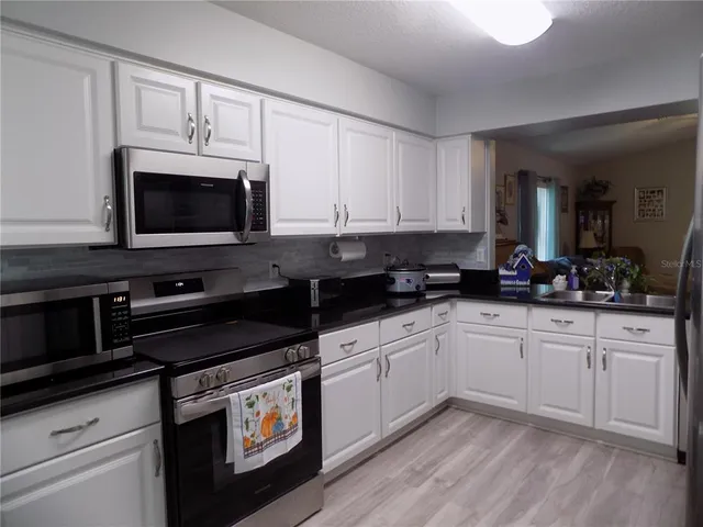 a kitchen with stainless steel appliances granite countertop white cabinets granite counter tops and a hard wood floors