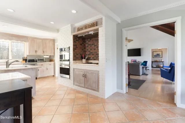 a view of living room kitchen with stainless steel appliances granite countertop a stove and a view of living room