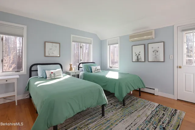 a bedroom with two beds and wooden floor