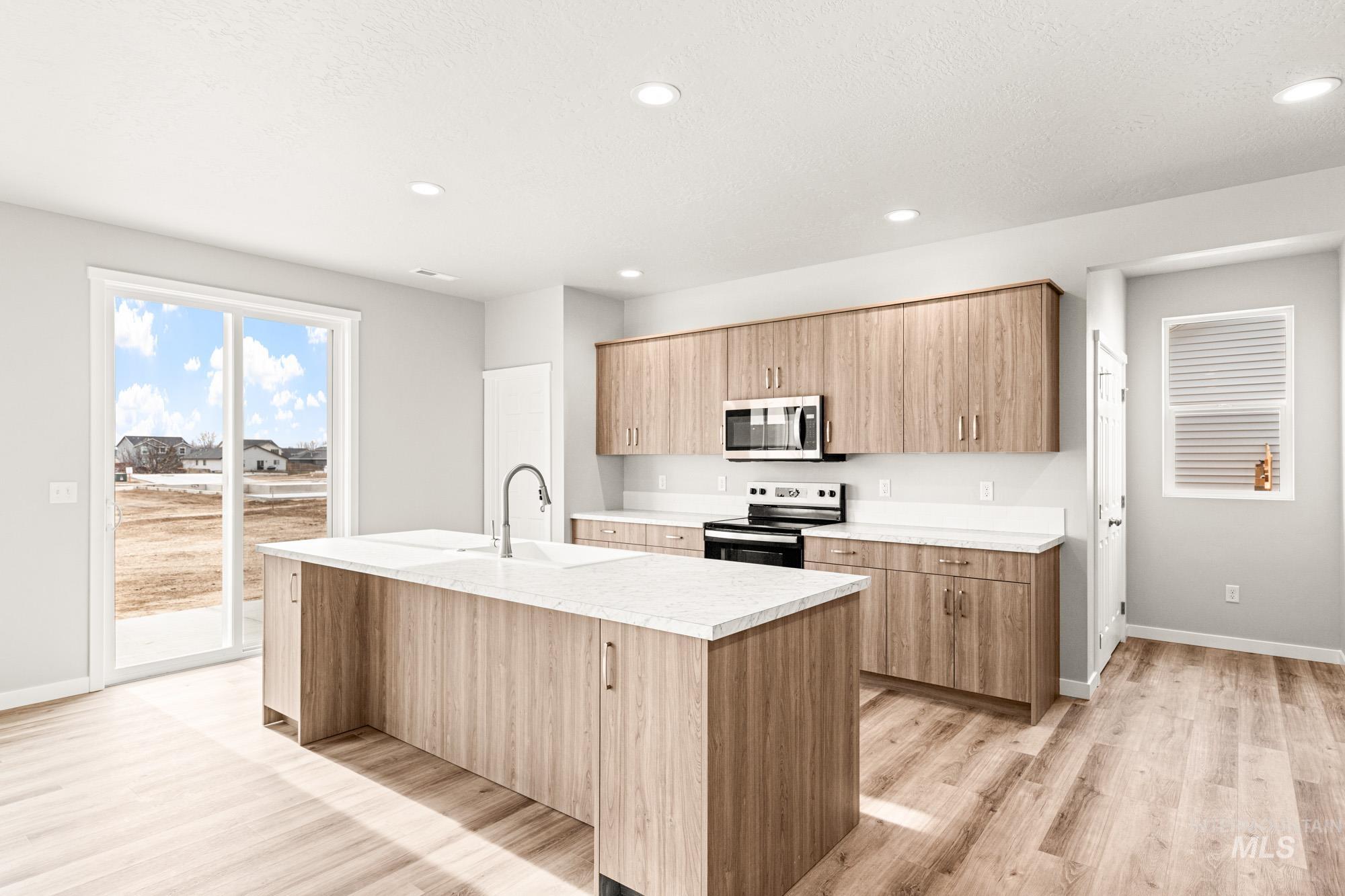 448 Merlin Court Middleton, ID 83644 - Photo 5 of 29 Kitchen featuring wood-finish cabinetry, stainless steel appliances, white countertops, and a center island with an integrated sink