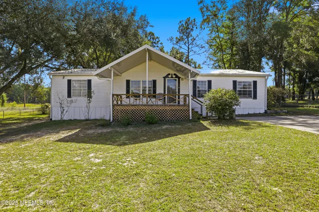 a front view of house with yard and trees in the background