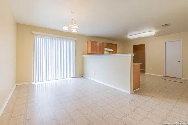 an empty room with kitchen view and wooden floor