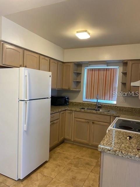 4565 Duhme Road, Unit 110 St. Petersburg, FL 33708 - Photo 5 of 13 a kitchen with granite countertop a refrigerator a sink and white cabinets