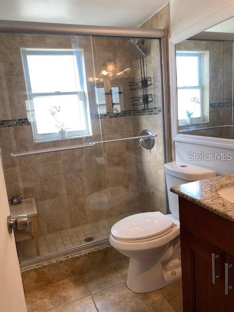 4565 Duhme Road, Unit 110 St. Petersburg, FL 33708 - Photo 7 of 13 a bathroom with a granite countertop toilet a sink and a shower