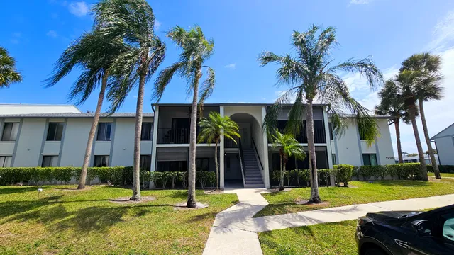 front view of a house with a yard and palm trees