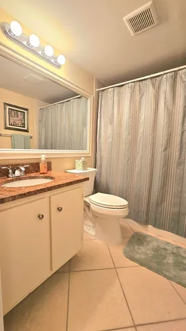 a bathroom with a granite countertop sink and a toilet