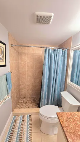 a bathroom with a granite countertop shower and a toilet